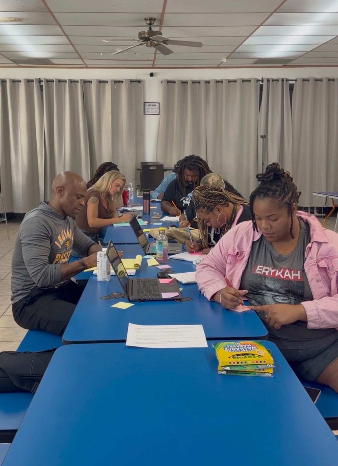 Coastal staff members writing individual reflections at long blue tables during the workshop
