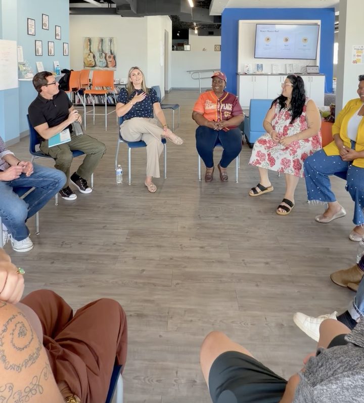 PBC Hub team members seated in a circle, smiling and talking during the workshop while Nicole Meyer speaks