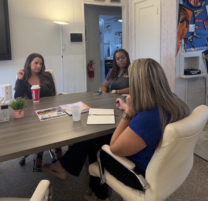 Nicole Meyer taking notes during a conversation with two leaders at a conference table
